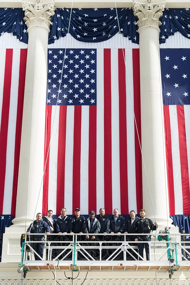 AOC employees in front of a flag near the inaugural platform on the U.S. Capitol's West Front.