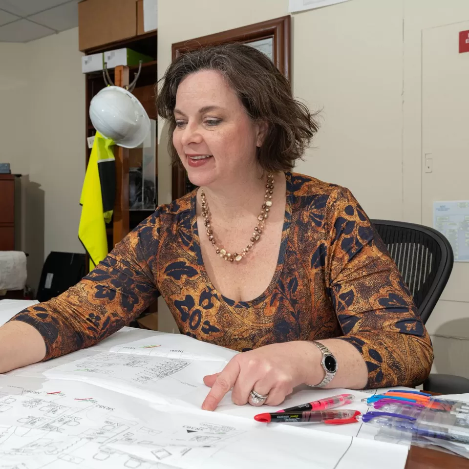 A person at a desk reviews room layout plans.