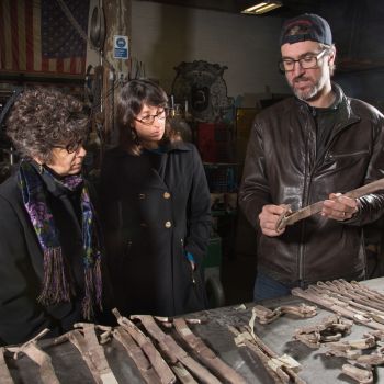 Three people looking at pieces of sculpture.