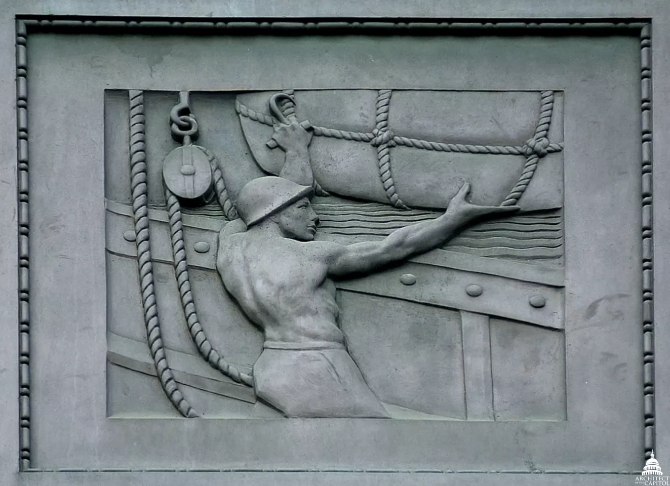 A sailor maneuvers cargo in a panel on exterior of the Dirksen Senate Office Building. 