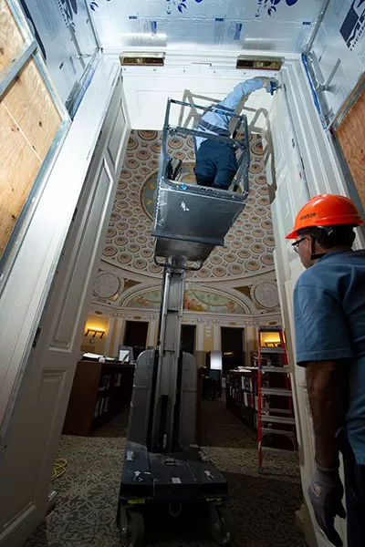 Woodcrafters refitting new door hinge locations on existing door frames in the Thomas Jefferson Building.