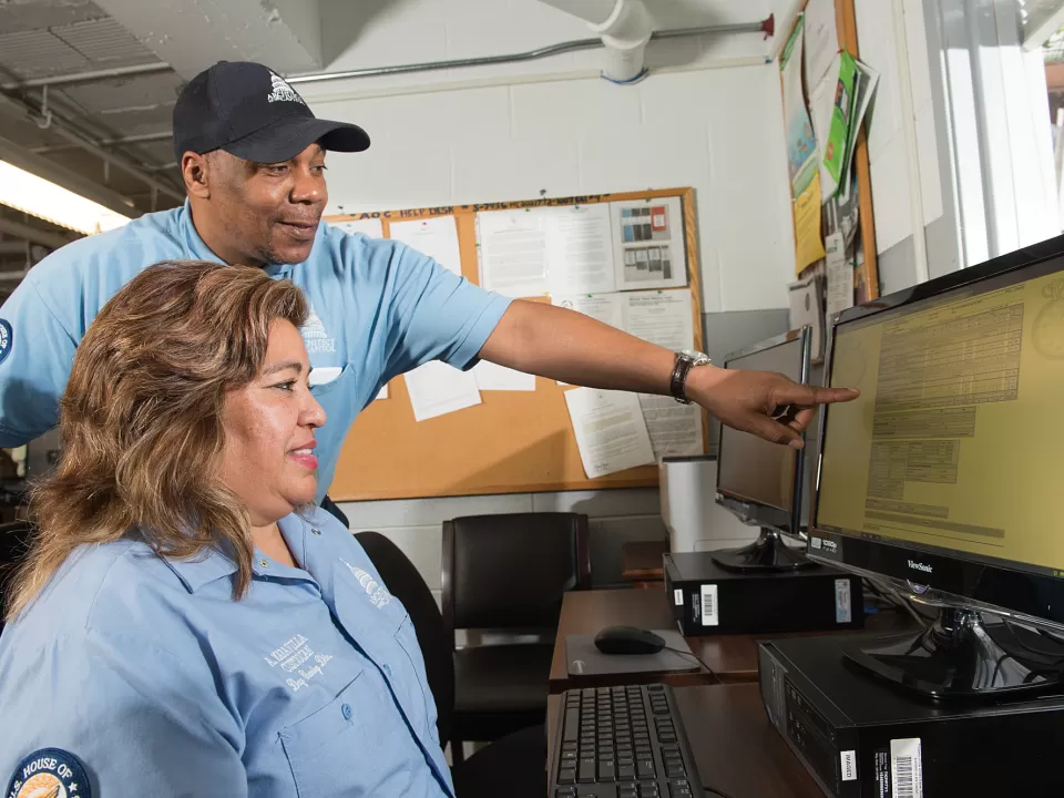 Two people looking at a computer monitor.